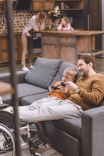 행복의 선택적 장애인 휠체어 조이스틱와 집에서 귀여운 아들에 다리와 아버지 — 스톡 사진