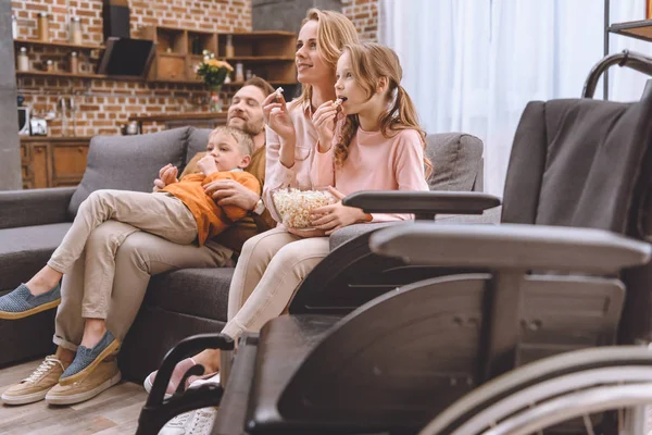 Vista Cerca Silla Ruedas Familia Sentada Sofá Comiendo Palomitas Detrás — Foto de Stock