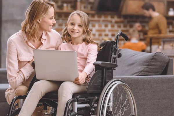 Happy Mother Looking Cute Little Daughter Sitting Wheelchair Using Laptop — Stock Photo, Image