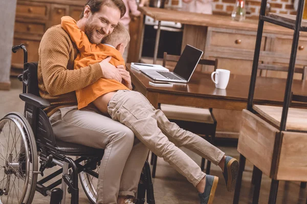 Happy Disabled Father Wheelchair Hugging Cute Little Son Home — Stock Photo, Image