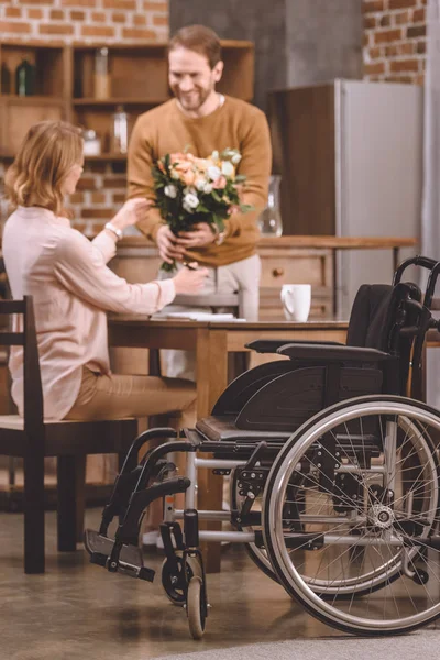 Крупный План Инвалидного Кресла Улыбающегося Мужчины Дарящего Цветы Жене Инвалиду — Бесплатное стоковое фото