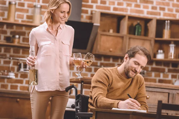 Lachende Vrouw Bedrijf Wijn Glazen Een Fles Terwijl Man Rolstoel — Gratis stockfoto