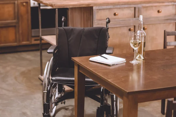 Cadeira Rodas Perto Mesa Com Garrafa Vinho Óculos Caderno Caneta — Fotografia de Stock