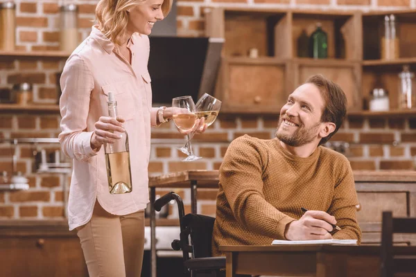 Sonriente Mujer Sosteniendo Copas Vino Botella Mientras Marido Discapacitado Silla — Foto de stock gratis