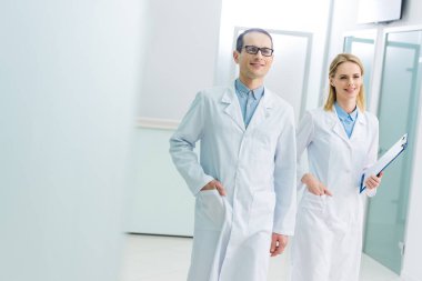 gülümseyen doktorlarla hastane koridorunda tanıda beyaz kat olarak