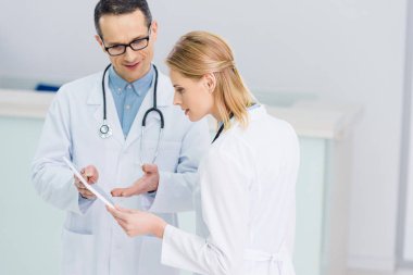 Doktorlar hastanede tanı tartışırken dijital tablet ile beyaz kat olarak