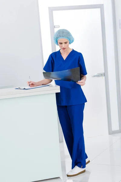 Kobiece Chirurg Ogląda Ray Pisania Diagnozy Poradni — Zdjęcie stockowe