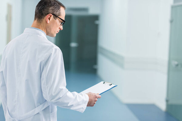 male doctor in white coat reading diagnosis in hospital