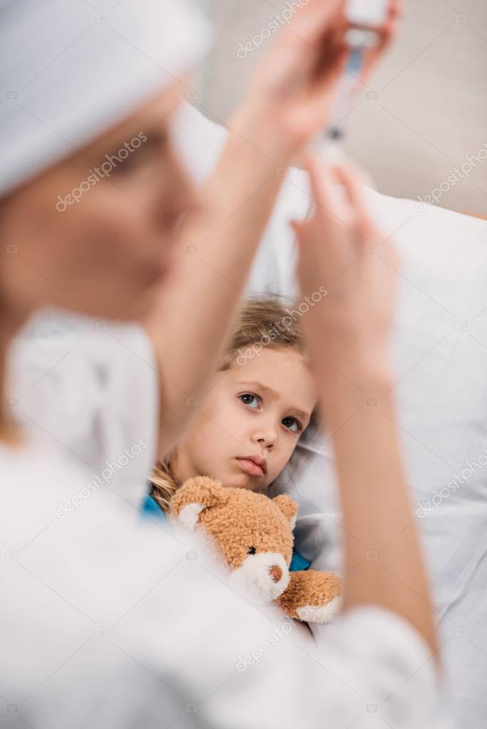 Female doctor preparing vaccination for ill scared kid