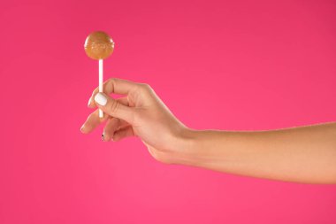 cropped image of girl holding lollipop in hand isolated on pink clipart