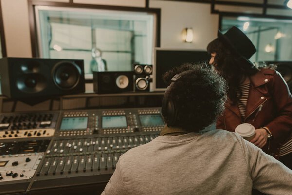 sound producers looking at singer at recording studio