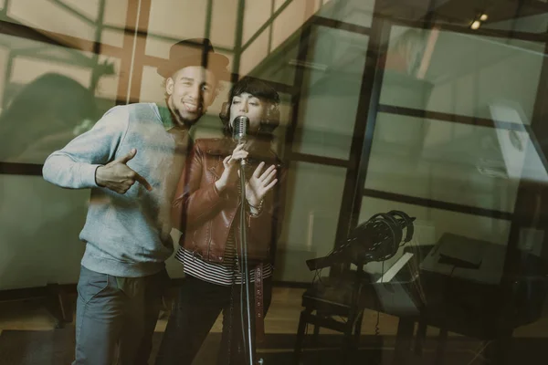 年轻歌手夫妇录音歌曲在玻璃在演播室 — 图库照片