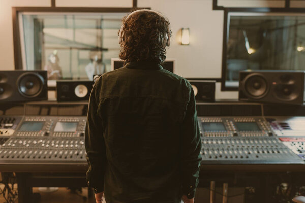 back view of sound producer in headphones at studio