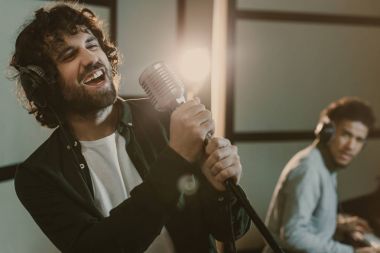 sanatsal delikanlı adam piyano arka plan üzerinde bulanık iken mikrofonla şarkı performans