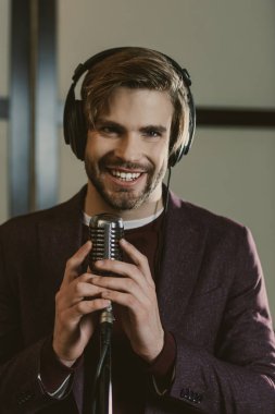 happy young singer in headphones standing with microphone clipart