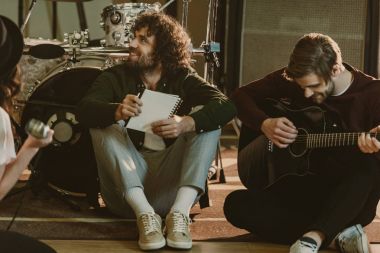 young music band sitting on floor with notepads and talking clipart