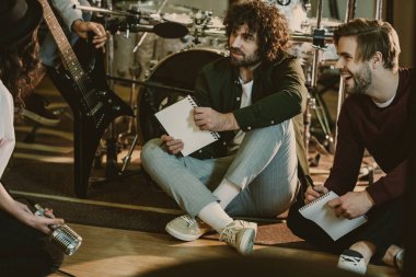 music band sitting on floor with notepads and talking clipart