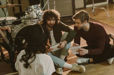 young band writing music together while sitting on floor clipart