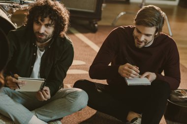 young music band colleagues writing lyrics together while sitting on floor clipart