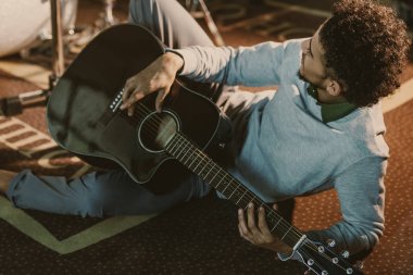 Afro-Amerikan yakışıklı ile akustik gitar Studio yerde yatarken