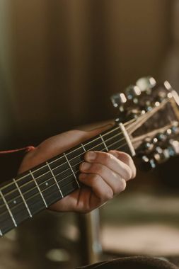 İnsan akustik gitar çalarken çekilen resim.