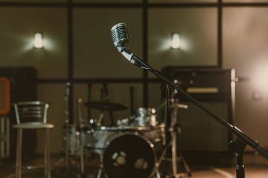 vintage microphone on stand against blurred drum set clipart