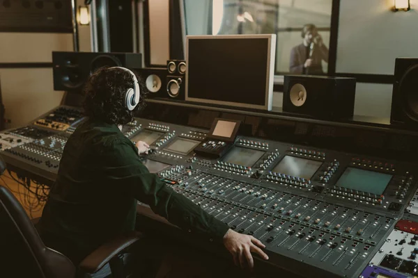 サウンド プロデューサーがスタジオで歌を録音しながら働いて — ストック写真