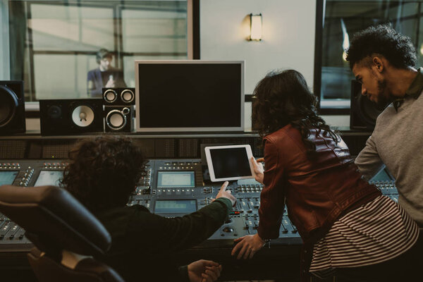 sound producers using tablet together at recording studio