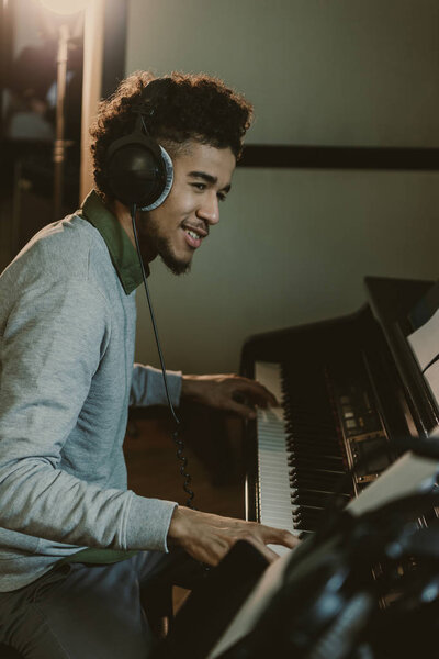 счастливый молодой африканский американец, играющий на пианино в студии
