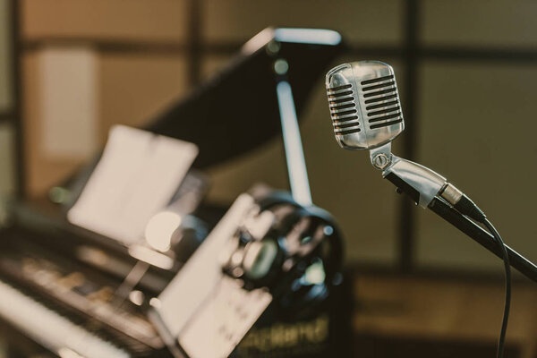 close-up shot of vintage microphone in front of blurred piano