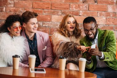 kahve yudumlarken Smartphone kullanarak moda çok ırklı gençler gülümseyen