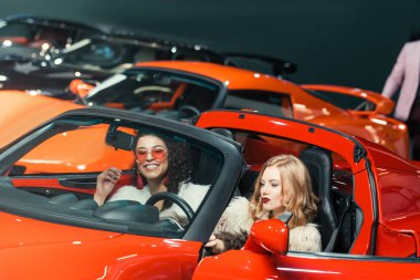 moda bir çok ırklı kadın lüks kırmızı araç içinde oturan gülümseyen