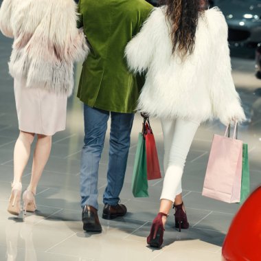 cropped shot of young shoppers walking by auto showroom clipart