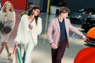 group of young shoppers walking by showroom and choosing car clipart