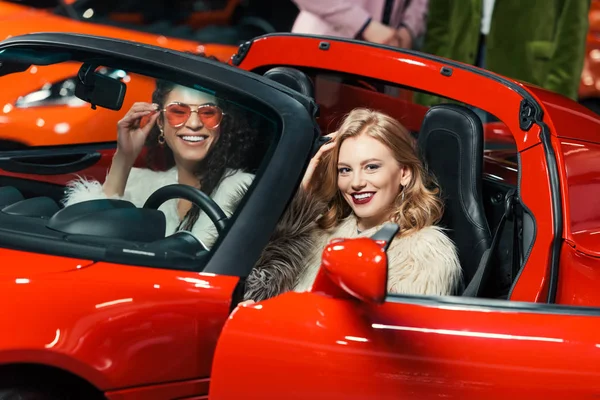 Fashionable Smiling Multiethnic Women Sitting Luxury Red Car Looking Camera — Stock Photo, Image