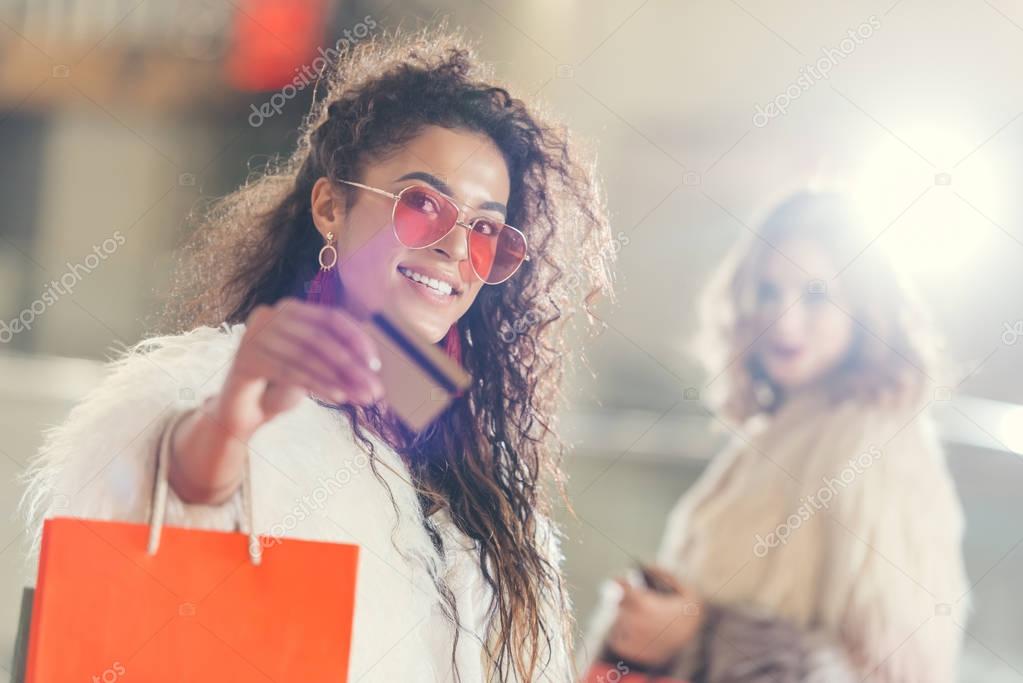 young stylish woman in fur coat with golden credit card on shopping