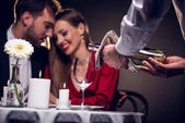Kellner schenkt Wein ein, während schönes Paar am Valentinstag ein romantisches Date im Restaurant hat
