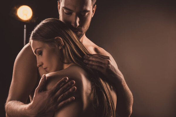 нежный парень обнимает обнаженного парня, на коричневом с задним светом
