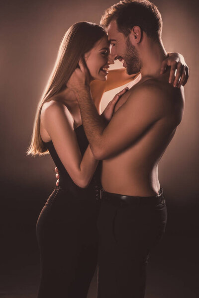 sensual couple laughing and hugging together, on brown with back light