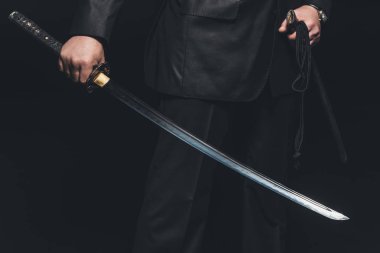 cropped shot of man with katana sword on black background clipart
