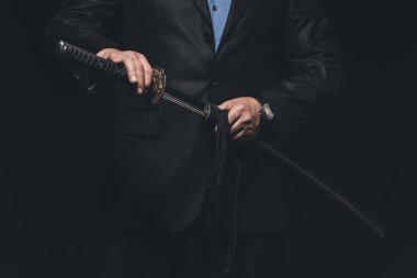 cropped shot of man in suit taking out his katana sword isolated on black clipart