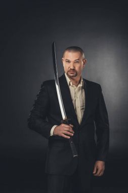 siyah kameraya bakarak katana kılıcı ile takım elbiseli adam