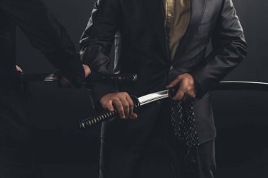 cropped shot of modern samurai taking out their swords isolated on black clipart