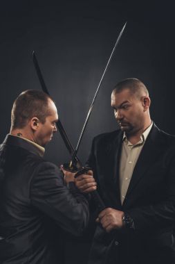 businessmen fighting with katana swords isolated on black clipart