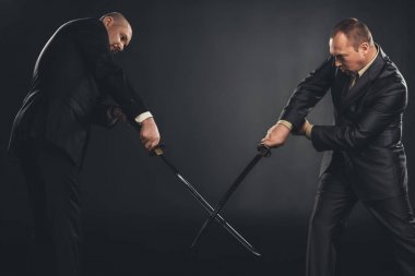 businessmen fighting with katana swords isolated on black clipart