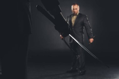 handsome modern samurai in suit ready to fight on black clipart