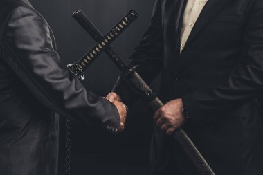 cropped shot of meeting of yakuza members in suits with katana swords isolated on black clipart