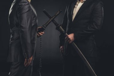 cropped shot of meeting of modern samurai in suits with katana swords isolated on black clipart