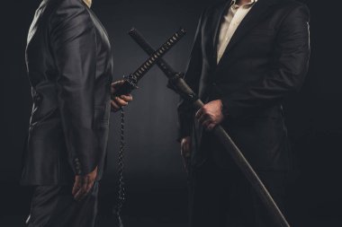 cropped shot of meeting of modern samurai in suits with katana swords isolated on black clipart