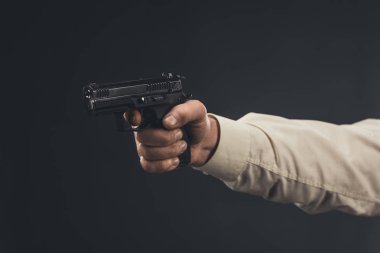cropped shot of man holding gun isolated on black clipart